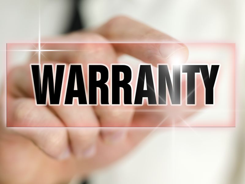 A hand holding up a sign that reads &ldquo;Warranty.&rdquo;